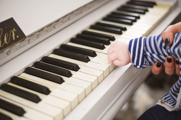 A small child plays the piano. In the frame of the hand on the keys.