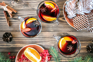 Mulled wine with spices and cookie on wooden rustic background, top view.