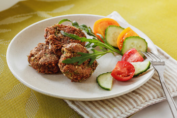 Lentils cutlet on a plate with vegetables and arugula, vegan source of protein, close-up, daylight