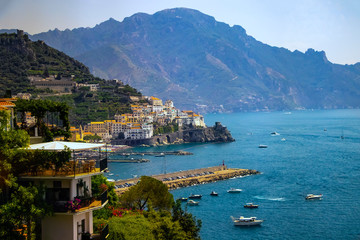 The view of Amalfi coast. This is on the south of Italy in Europe. The city stands on cliffs above the sea. There are boats on the sea. 