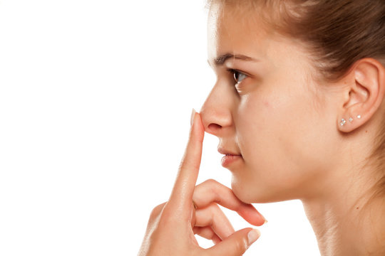 Profile of young woman touching her nose on white background