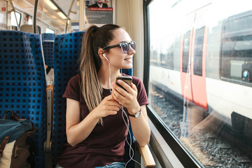 A young girl listens to a music or podcast while traveling in a train.