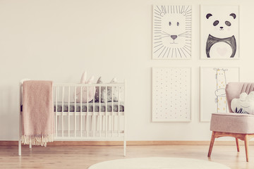 Bright baby room with white nursery with cute pillows and pink blanket, animals drawings on the wall next to comfortable armchair - obrazy, fototapety, plakaty