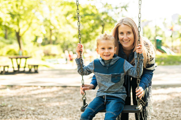 happy mother swinging daughter at the park