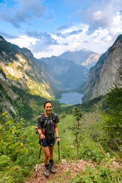 Young woman posing with walking sticks, hiking, mountaineering, view from the Rothsteig to the Obersee, Konigsee, Alps, mountain landscape, Berchtesgaden National Park, Berchtesgadener Land, Upper Bavaria, Bavaria, Germany, Europe