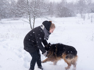 Girl playing with dog in winter in the snow