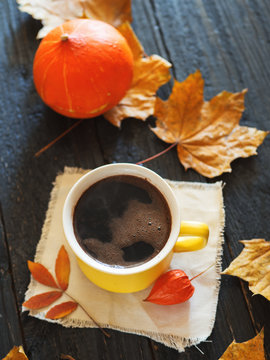 Hot coffee or chocolate in a mug on a dark background with dry leaves