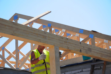 Roofer contractor building house roof beams, trusses, wooden frame beams on rooftop.