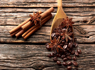 Coffee, anise, cinnamon  in wooden spoon on wooden background.