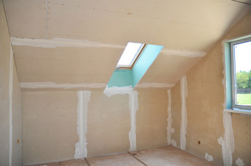 Drywall construction in unfinished house attic with skylight. Drywall gypsum board interior tape...