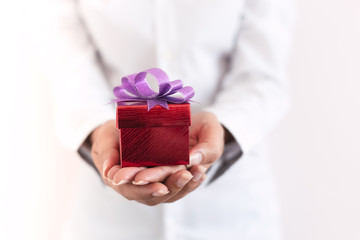 woman hand  showing the gift in a box,holding red Gift box with bow over holiday background which celebrating.