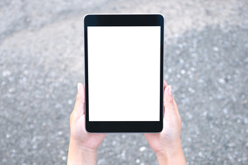 Top view mockup image of hands holding black tablet pc with blank white screen with street background