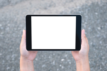 Top view mockup image of hands holding black tablet pc with blank white screen with street background