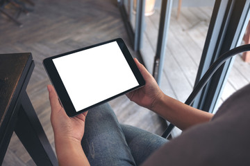 Mockup image of a woman sitting and holding black tablet pc with blank white desktop screen