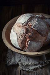 Brown loaf of bread on dark and rustic table