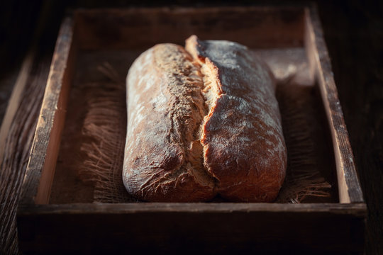 Closeup of loaf of bread on dark and rustic table