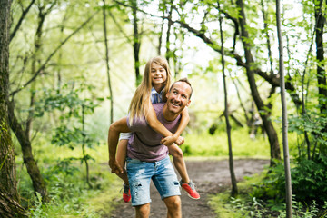 Father giving his daughter a piggyback ride, having fun
