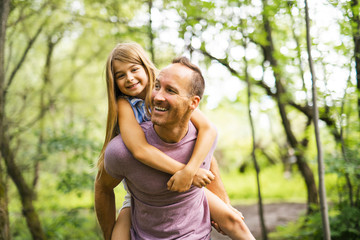 Father giving his daughter a piggyback ride, having fun