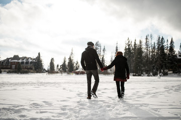 Fototapeta na wymiar Couple holding each other's hands and walking on snow