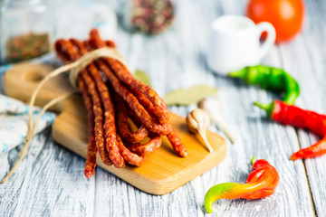 meat sausages with spices and chili peppers on a wooden board