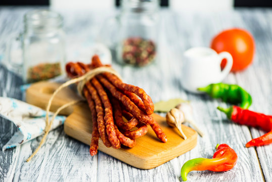 meat sausages with spices and chili peppers on a wooden board