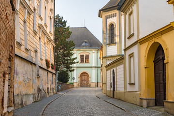 Cobblestone street cityscape with baroque and dilapidated buildings in the old town of Olomouc, Czech Republic. 