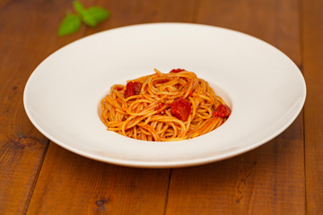 Plate of delicious Italian spaghetti pasta with fresh basil leaves,  with meat, tomato sauce, vegetables and grated parmesan cheese