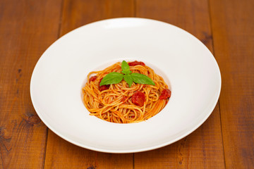 Plate of delicious Italian spaghetti pasta with fresh basil leaves,  with meat, tomato sauce, vegetables and grated parmesan cheese
