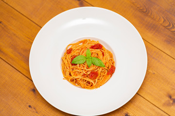 Plate of delicious Italian spaghetti pasta with fresh basil leaves,  with meat, tomato sauce, vegetables and grated parmesan cheese