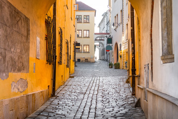 Narrow cobblestone street leading upwards flanked by historical buildings in the old town of...