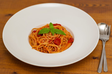 Plate of delicious Italian spaghetti pasta with fresh basil leaves,  with meat, tomato sauce, vegetables and grated parmesan cheese