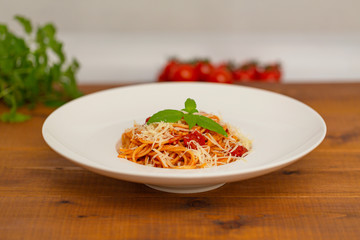 Plate of delicious Italian spaghetti pasta with fresh basil leaves,  with meat, tomato sauce, vegetables and grated parmesan cheese