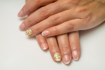 Naklejka premium French manicure and nail gel Polish. The decoration of the nail white and gold decor. Top view Close-up photography