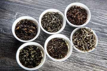 closeup assorted tea leaves in six white small round vessels
