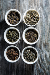 top view on assorted tea leaves in six white small round vessels