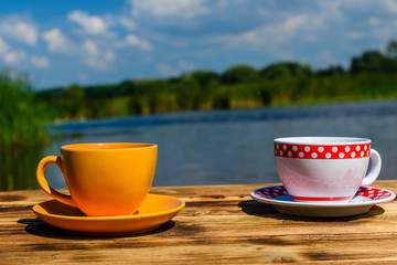 Two cups of coffee on wooden table at the riverside