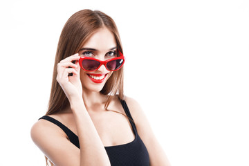 Successful brunette woman wearing black dress and sunglasses smiling and looking out of glasses on the white background, concept of consumerism, sale, rich life