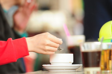 Woman holding a spoon and cup of coffee in cafe, while having relax times in the morning