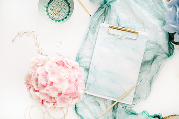 Artist home office desk workspace with watercolor clipboard, paintbrush, turquoise blanket, colorful pastel hydrangea flower bouquet, woman fashion accessories on white background.