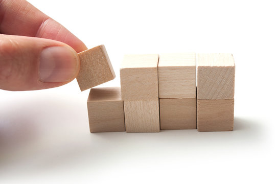 closeup of hand with wooden brick of construction game on white background