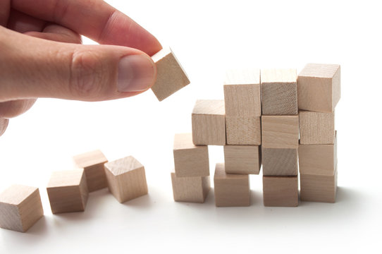 closeup of hand with wooden brick of construction game on white background