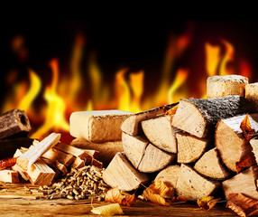 Stacked dried logs in front of a burning fire