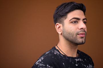Young handsome Indian man against brown background