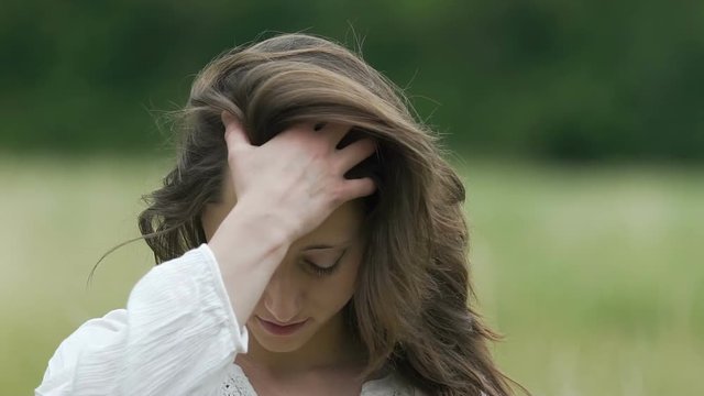 Beautiful woman combs her hair with hand enjoys herself outdoors slow motion