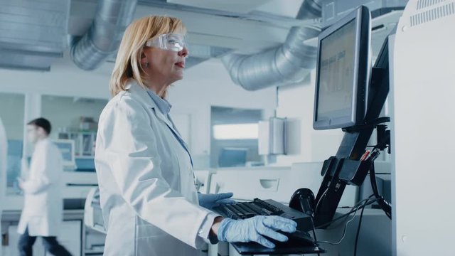Female Scientists Programs Medical Equipment with Personal Computer. Team Of Professionals Working in Pharmaceutical Research Modern Laboratory.