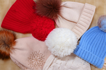 Multicolored warm hats lie on a fluffy soft rug. Autumn and winter concept