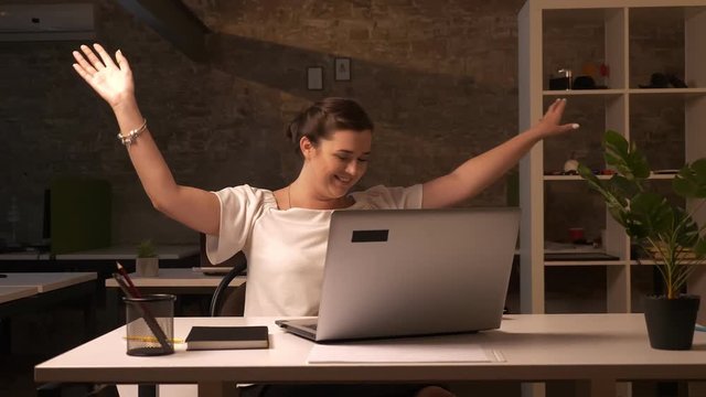 Happy laughing caucasian businesswoman is stewing her documents around office while sitting in brick studio isolated, having fun