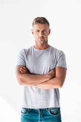 Obraz premium handsome adult man in blank grey t-shirt looking at camera with crossed arms isolated on white