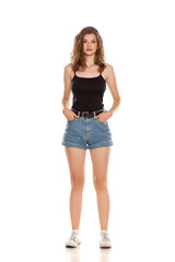 Young pretty woman in short jeans standing on white background