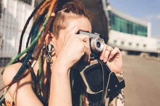 young girl with tattoo and dreadlocks takes pictures on urban industrial background